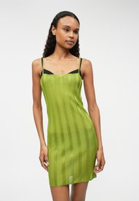 Zelené pletené mini šaty s vertikálními pruhy, tenkými ramínky a přiléhavým střihem. Mají kulatý výstřih a lehký, texturovaný materiál.
