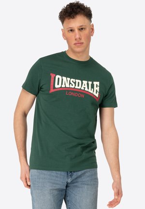 Grøn bomulds t-shirt med et buet "LONSDALE" logo i hvid og rød. Korte ærmer, rund hals og afslappet pasform.