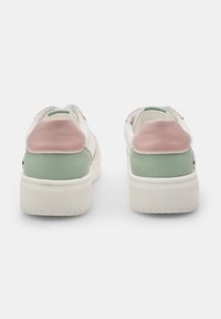 White sneakers with a pink and green leather heel, contrasting stitching, and a textured sole. Features a minimalist design and soft materials.