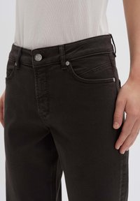 Zwarte denim jeans met een slim fit, voorzien van een rits en metalen knoopsluiting en zijzakken. Glad textuur met subtiele stikdetails.