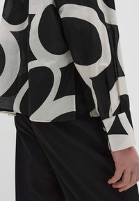 Camicia a maniche lunghe bianca e nera con un audace motivo astratto, realizzata in tessuto leggero con polsini a bottoni e vestibilità rilassata.