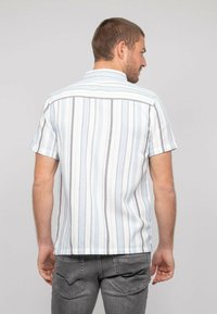 Chemise à manches courtes avec des rayures verticales bleu clair, blanches et grises ; tissu texturé avec un col boutonné et un ourlet droit.