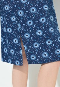 Tmavě modrá látková sukně s motivem slunce a měsíce, s bočním rozparkem a jemnou texturou. Design zahrnuje nebeské vzory v bílé a světle modré barvě.