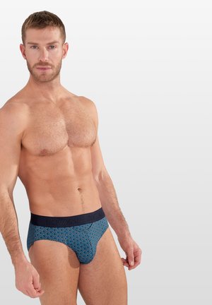 Blaue gemusterte Boxerunterhose mit einem marineblauen Bündchen, auf dem der Markenname steht. Der Stoff hat eine weiche Textur und sorgt für einen engen Sitz.