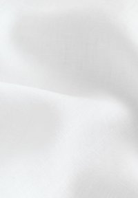 Tissu blanc lisse avec des plis doux et une texture fine, éclairé de manière uniforme sur un fond uni.