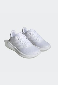 White athletic shoes with a mesh upper, textured detailing, and three horizontal stripes on the side; cushioned sole with a slight curve.