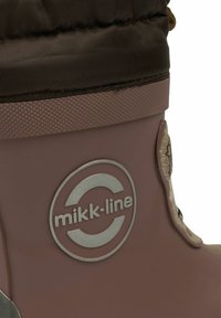 Botte en caoutchouc rose avec un revers en tissu brun foncé texturé, logo argenté, et un détail de motif sur le côté. Matériau durable avec un design flexible.