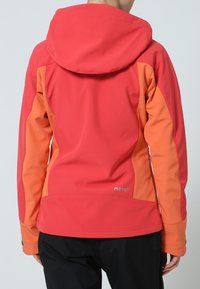 Veste softshell rouge et orange avec capuche, présentant une texture lisse et des panneaux latéraux contrastants. Logo près de l'ourlet. Conçue pour une utilisation en extérieur.