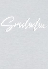 Jasnoszara tkanina o gładkiej teksturze z białym, wypukłym napisem "Smilodox" w kursywie na środku.