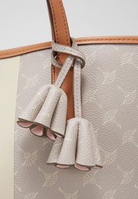 Grijze leren tote bag met textuur en een crèmekleurige binnenkant, met een geknoopte bruine band en twee decoratieve franjes.