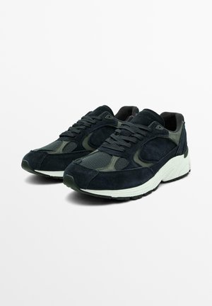 Sneakers di un blu scuro, realizzati con materiali in suede e mesh, con punta arrotondata, zeppa bianca spessa e suola in gomma nera testurizzata.