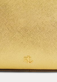 Aukso tekstūros rankinė su subtiliu raštu, su iškilniu "RL" logotipu auksu apatiniame dešiniajame kampe.