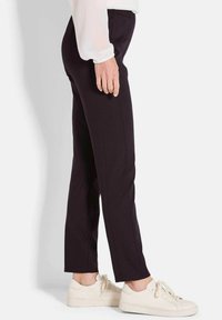 Zwarte op maat gemaakte broek met een recht gesneden ontwerp, voorzien van een gladde textuur en zijnaden, en gecombineerd met lichtgekleurde sneakers.