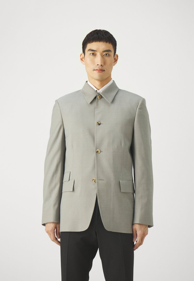 Light gray tailored jacket with a high collar, button front, and two front pockets. Features a smooth texture and clean lines.