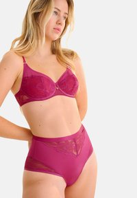 Ensemble de lingerie fuchsia composé d'un soutien-gorge en dentelle à motif floral et d'une culotte taille haute, tous deux en tissu lisse avec des accents décoratifs.