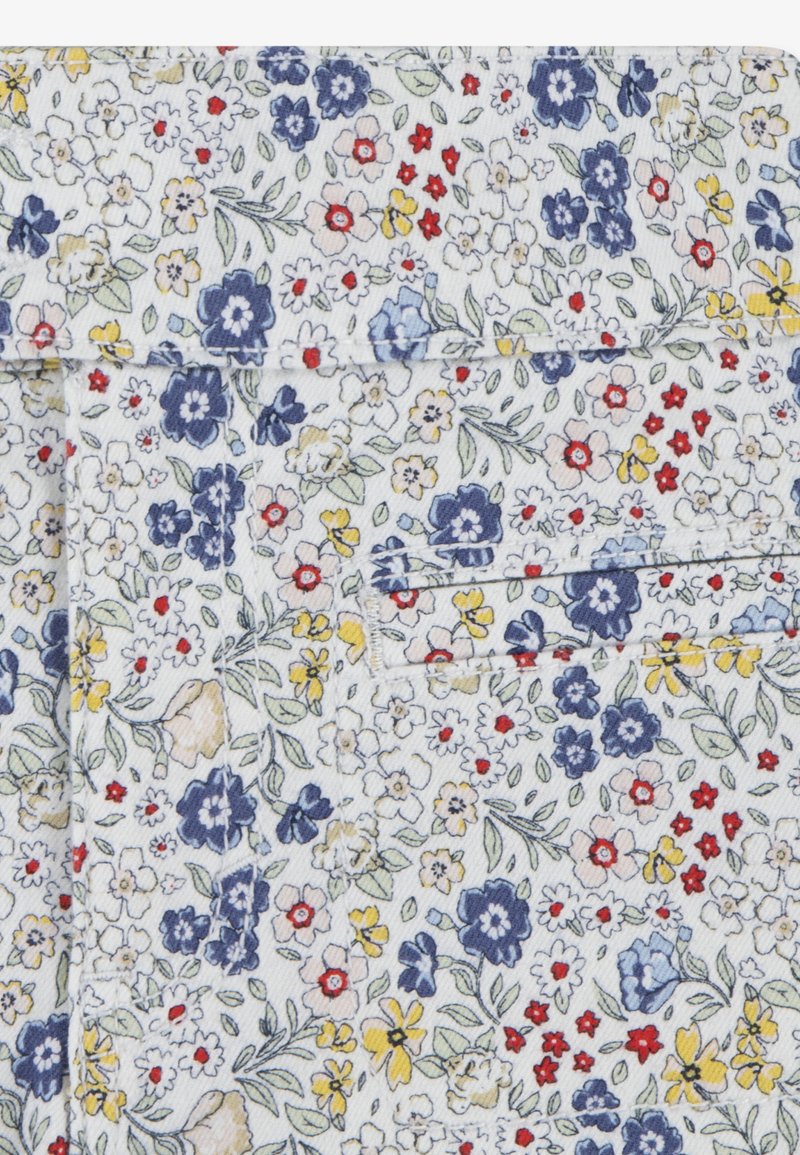 Chemise à manches courtes avec un fond blanc, ornée d'un motif floral en bleu, jaune, rouge et vert. Coupe ajustée avec une texture douce.