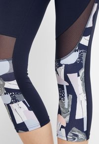 Leggings azul marino con patrones abstractos en tonos pastel y detalles de malla. Confeccionados con un material elástico y un diseño ajustado.