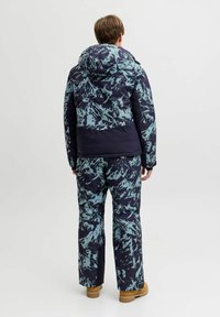 Giacca invernale e pantaloni navy con un motivo astratto blu chiaro. Dotati di cappuccio e realizzati in materiale isolante. Progettati per il freddo.
