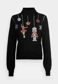 Pull-over à col roulé noir avec des motifs en sequins représentant un danseur et un soldat de jouet, accompagnés d'étoiles argentées et colorées suspendues en dessous. Tissu doux et texturé.