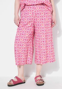 Roze culottes met een bloemmotief, met een wijdere pasvorm en een elastische tailleband. Gecombineerd met roze instappers met geschulpte randen.