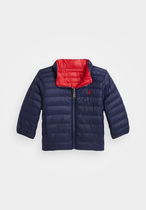 Doudoune navy avec un intérieur rouge, design matelassé horizontal, fermeture éclair et petit logo sur la poitrine. Manches longues et large col.
