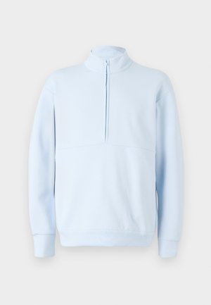 Šviesiai mėlynas džemperis su aukštu apykakle ir užtrauktuku. Turtinga lygi tekstūra ir ilgomis rankovėmis, sukurtas patogiam prigludimui.