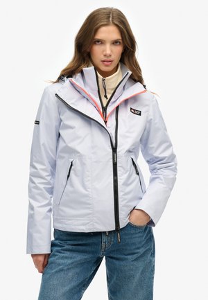 Chaqueta azul claro con un cuello alto, cremalleras negras y detalles en naranja. Incluye dos bolsillos laterales y una capucha. Material impermeable.