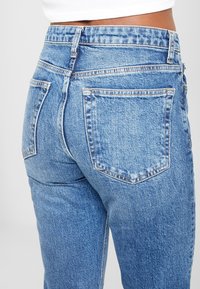 Högtaljade blå denimjeans med en klassisk femfickdesign och en något urtvättad look med synliga söm detaljer.