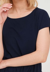 Granatowa bluzka z krótkim rękawem o szerokim dekolcie, wykonana z miękkiej dzianiny, z delikatnym stretch'em i gładką fakturą.