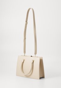Beige structured handbag with two short handles and a long adjustable strap. Smooth material with gold-tone hardware accents.