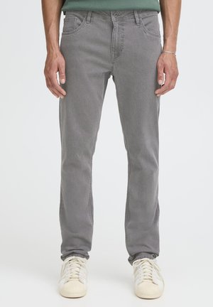 Grå denimjeans med smal passform, femlommers design og subtil tekstur; kombinert med off-white sneakers for kontrast.