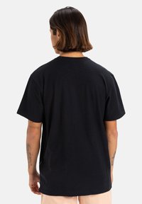 T-shirt in cotone nero con una vestibilità comoda, maniche corte e collo rotondo. Nessun logo o motivo visibile, texture liscia. Vista posteriore.