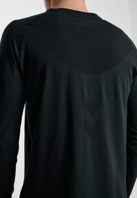 Zwarte longsleeve shirt met een gestructureerde achterkant, een gladde bovenkant en een subtiel chevronpatroon in het midden.