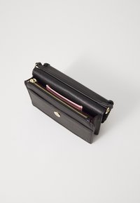 Black leather wallet with gold zipper, featuring a pink inner compartment, smooth texture, and a rounded hardware logo on the front.