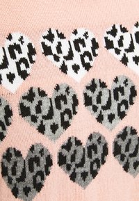 Pletený svetr s bledě růžovým pozadím a vzorem srdcí v černé, bílé a šedé leopardí potisku. Texturovaný design tkaniny.