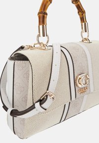 White handbag with textured fabric, vertical stripes, gold hardware, and bamboo handle. Features logo detail and adjustable shoulder strap.