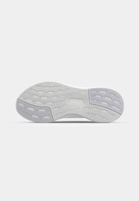 Semelle d'une chaussure de sport blanche avec un motif de bande de roulement texturé pour l’adhérence, affichée sur un fond gris clair uni.