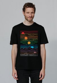 Schwarzes Baumwoll-T-Shirt mit einem bunten Grafikdesign von Sonnen, Linien und Bergen in lebendigen Farben, dargestellt auf einem rechteckigen Design.