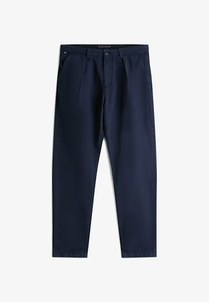 Un pantalon bleu marine avec une texture lisse, doté d'une fermeture à bouton et à zip, de deux poches avant et d'une étiquette de marque discrète à la taille.