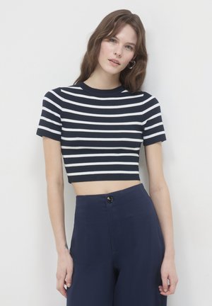 T-shirt cropped a righe navy e bianche con maniche corte, texture a costine, scollatura rotonda, abbinata a pantaloni navy a vita alta.