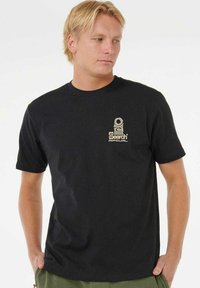 Sort kortærmet bomulds T-shirt med et lille cremefarvet logo på venstre bryst. Enkel design med rund hals og afslappet pasform.