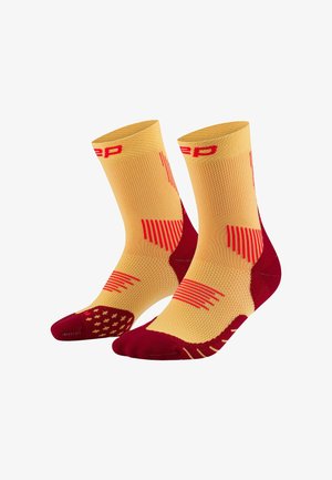 Gelbe und rote Sportsocken mit einem strukturierten Design, einem gerippten Oberteil, gepolstertem Fersenbereich und gemusterten Akzenten auf dem Fußbett.