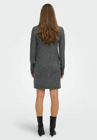 Robe tricotée grise avec manches longues, ourlet côtelé et design ajusté, assortie à des bottines noires à la cheville. Texture lisse, style minimaliste.
