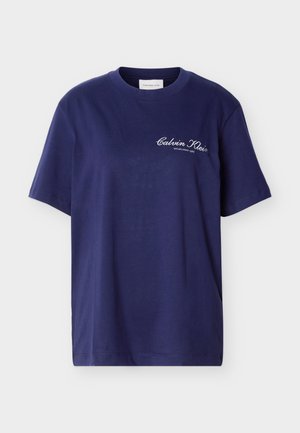 Tumši zils īsroku T-krekls ar apaļu izgriezumu un baltu uzrakstu "Calvin Klein Established 1968" uz kreisās krūtis augšējās puses.