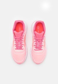 Zapatillas deportivas rosas con una parte superior de malla, cuello acolchado y suelas blancas. Presenta cordones a tono y un patrón texturizado en la zona de los dedos.