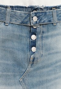 Jean en denim taille haute couleur bleu clair avec ourlet effiloché, comportant cinq boutons en métal argenté et des passants de ceinture standard.