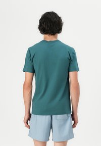 Türkisfarbener, kurzärmeliger T-Shirt aus weichem Stoff mit Rundhalsausschnitt. Kombiniert mit hellblauen Shorts, beide mit einem lässigen Schnitt.