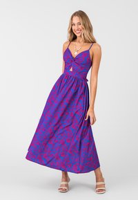 Langes lila Maxikleid mit pinkem Blumenmuster. Es hat einen gedrehten Vorderteil, verstellbare Spaghetti-Träger und eine taillierte Passform.