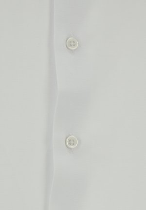 Camisa de algodón blanca con una textura suave, que presenta una fila de dos botones blancos y líneas limpias y simples. Sin patrones ni gráficos.