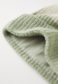 Kötött sapka világoszöld bordázott külssel és puha fleece béléssel. Texturált kötött mintákkal és hajtott peremmel a megnövelt melegség érdekében.